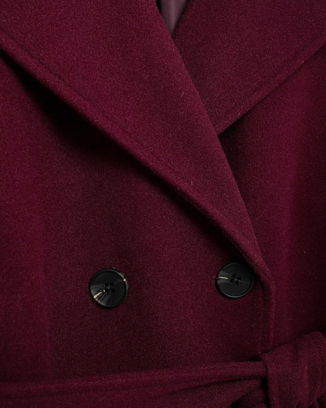 Close-up of burgundy tricot trench coat lapel and black buttons